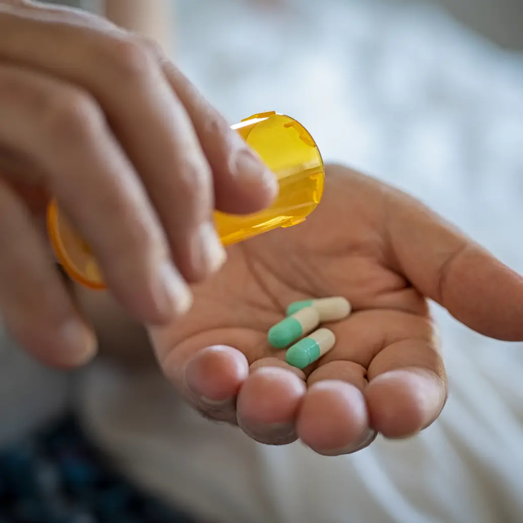 photo of someone emptying a prescription bottle of capsules into their own hand