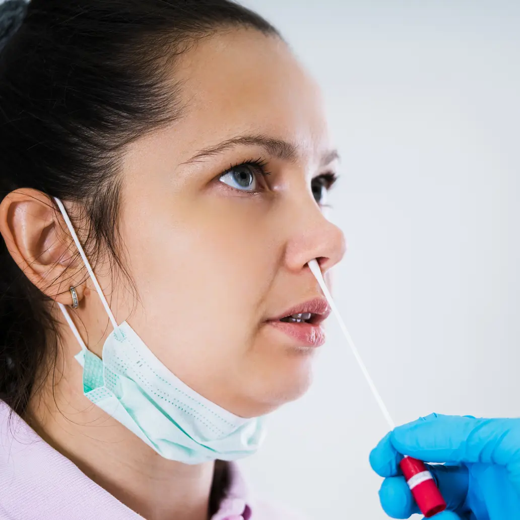 photo of a female patient receiving a nasal-pharyngeal swab in a clinic setting