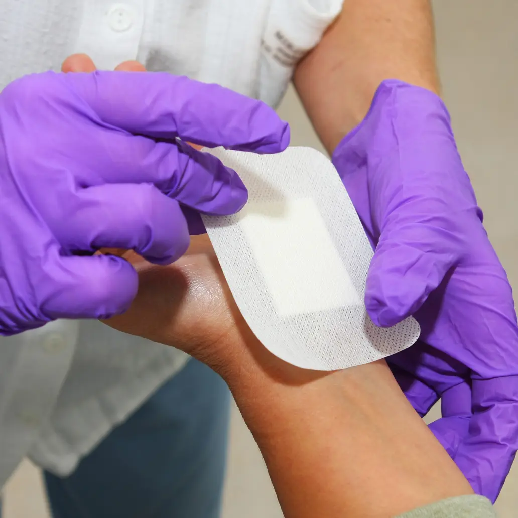 photo of a medical professional using an adhesive bandage to protect an incision from exposure to infection