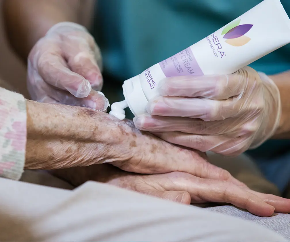 photo of a caregiver applying Thera Advanced skin cream to an elderly patient's hand