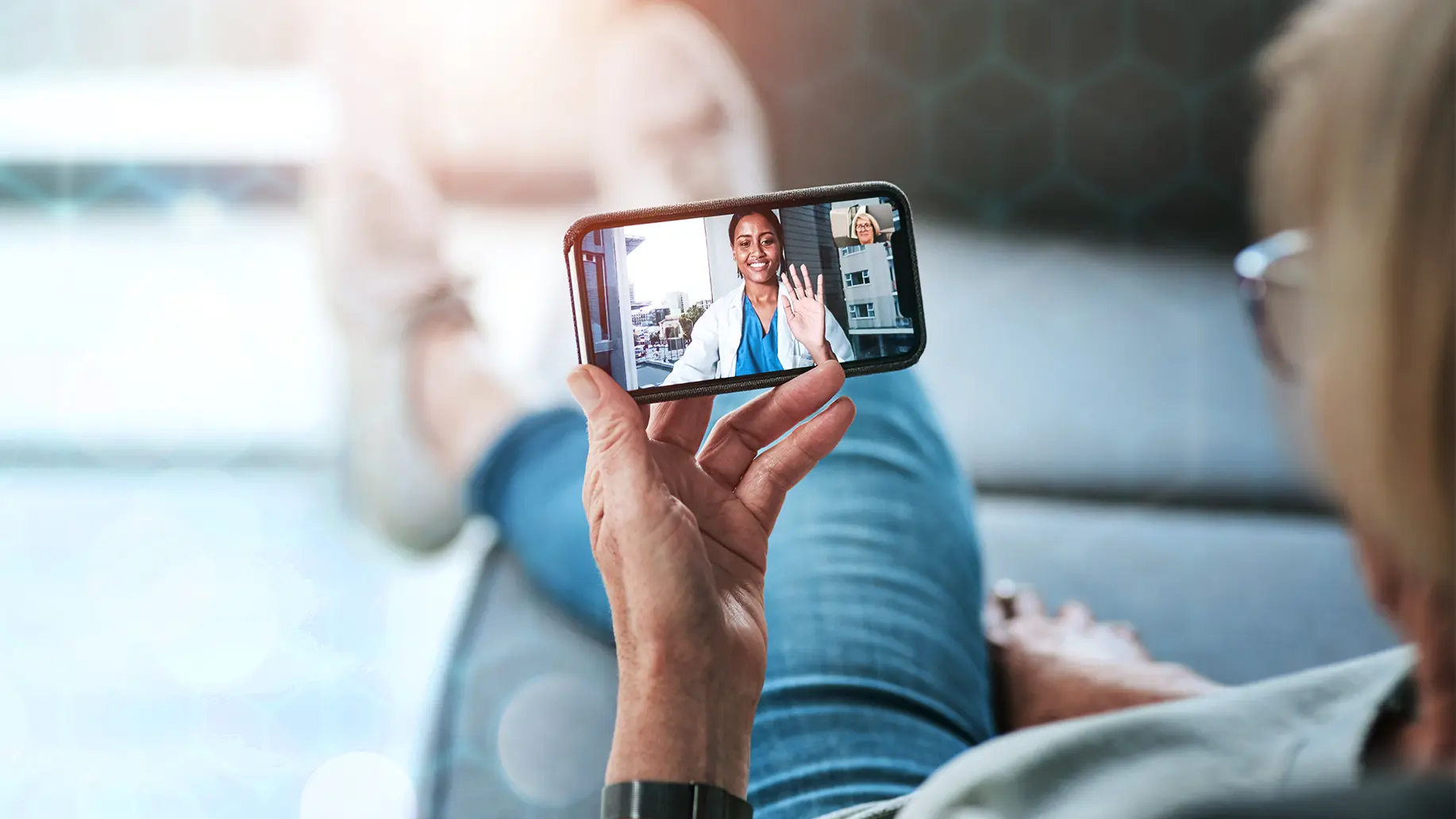 photo of a patient using their mobile phone for a telehealth call with their female doctor on the screen
