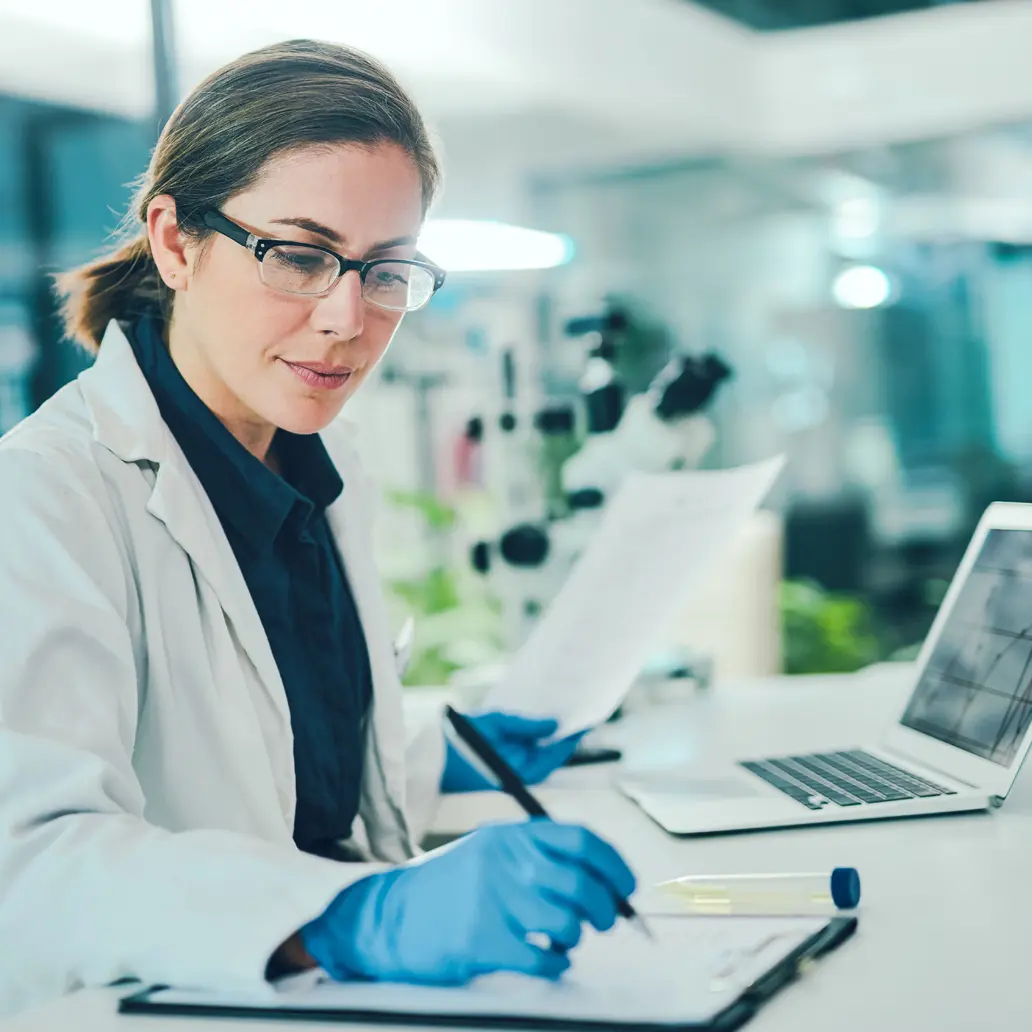 photo of a female lab technician recording results from a test