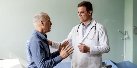 photo of a male doctor consulting with an older male patient in a clinic setting
