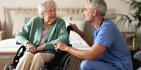 photo of a healthcare professional speaking to an elderly female patient in a wheelchair