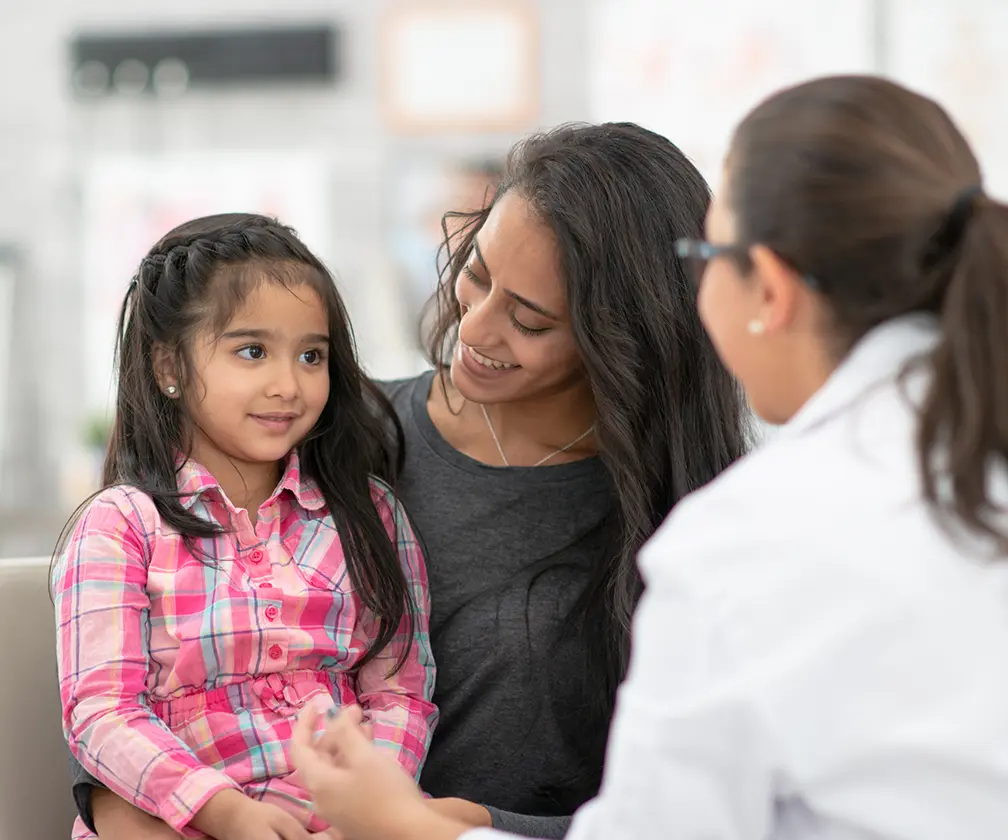 photo of a mother and child patient speaking to a doctor in an exam room setting