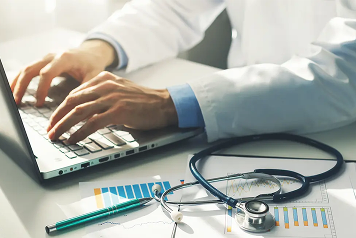 photo of a doctor typing on a laptop