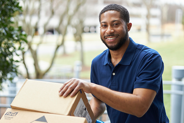 photo of a delivery professional with packages stacked on a handheld dolly
