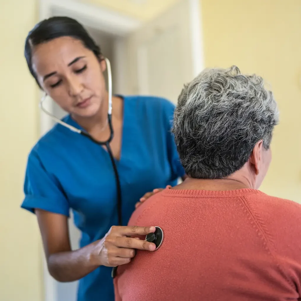 photo of a nurse using a stethoscope on the upper back of an older female patient