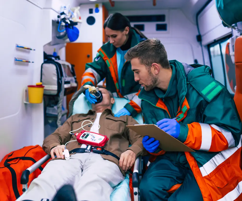 photo of EMS workers in an ambulance placing a respiratory mask on a patient