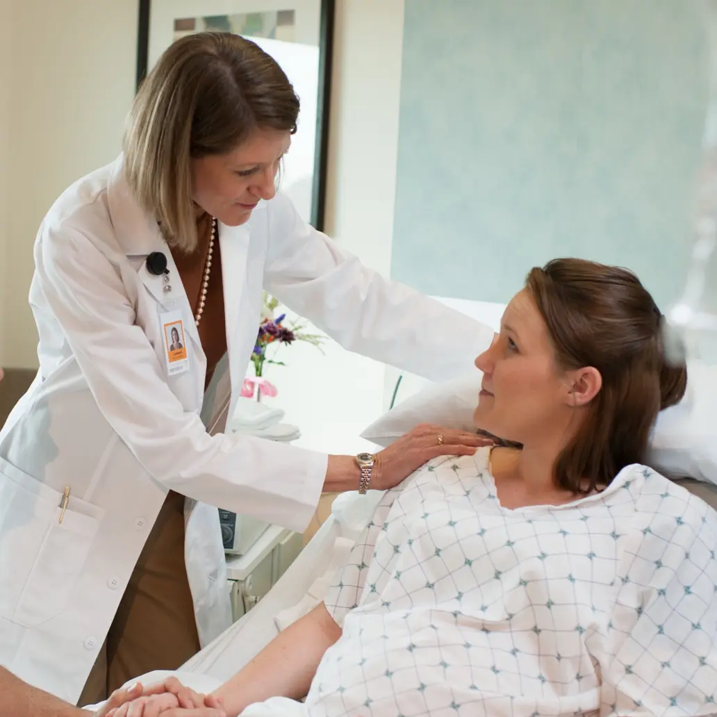 photo of a female doctor comforting a female patient in a hospital bed