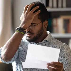 photo of man clutching his head after reading a document