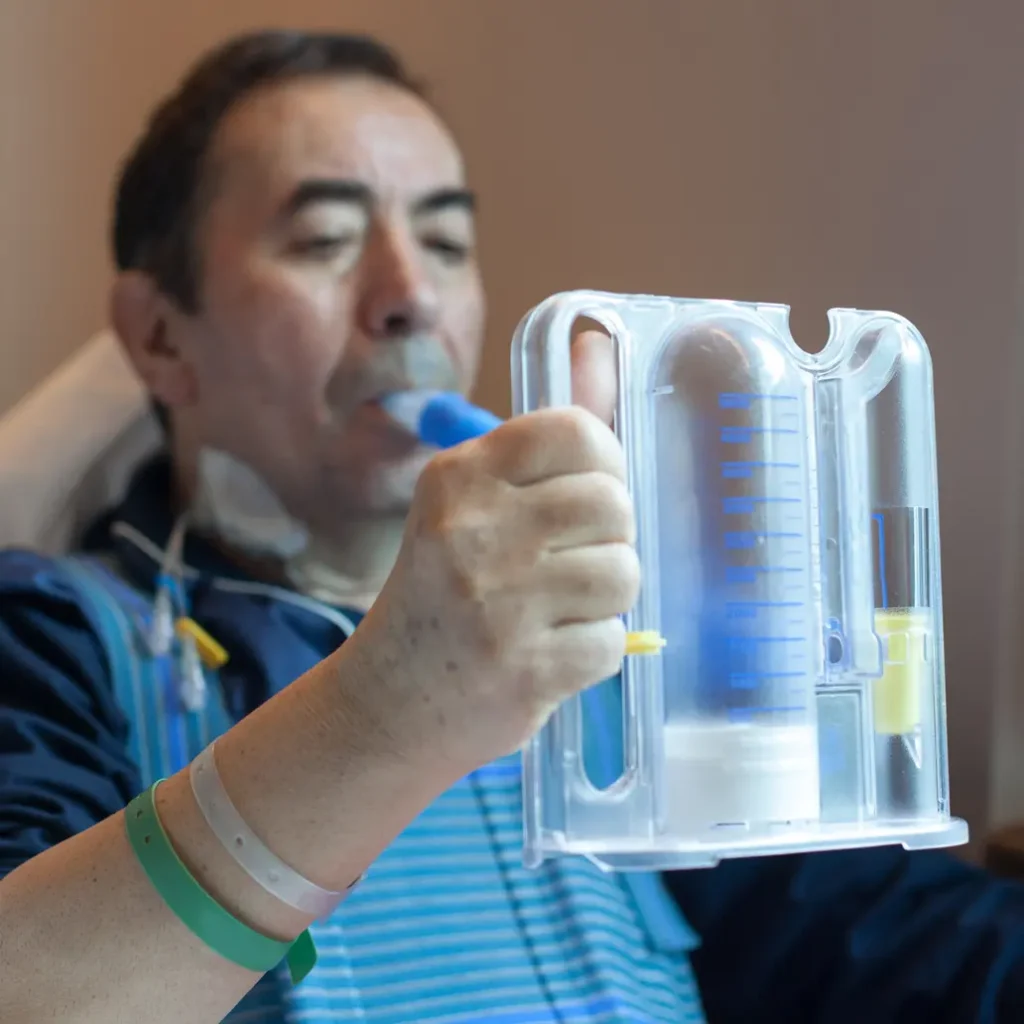 photo of an older male patient breathing into a spirometer to test for pneumonia