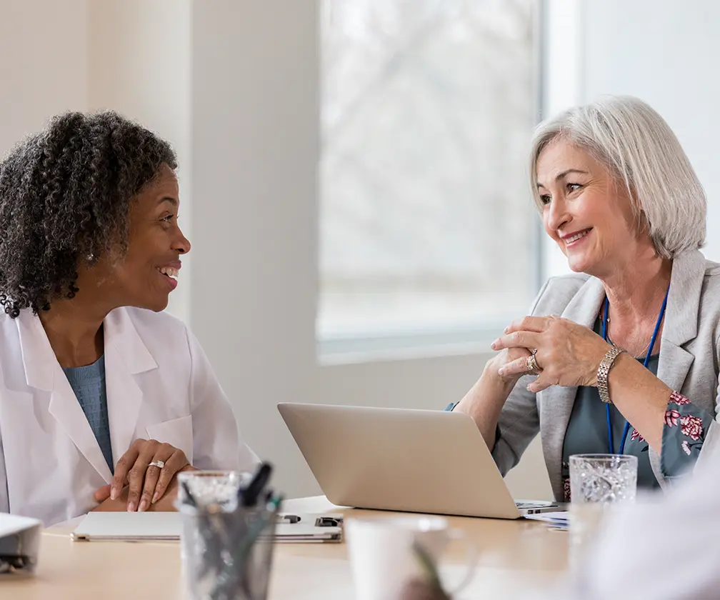 photo of a female consultant speaking to a female doctor in an office setting